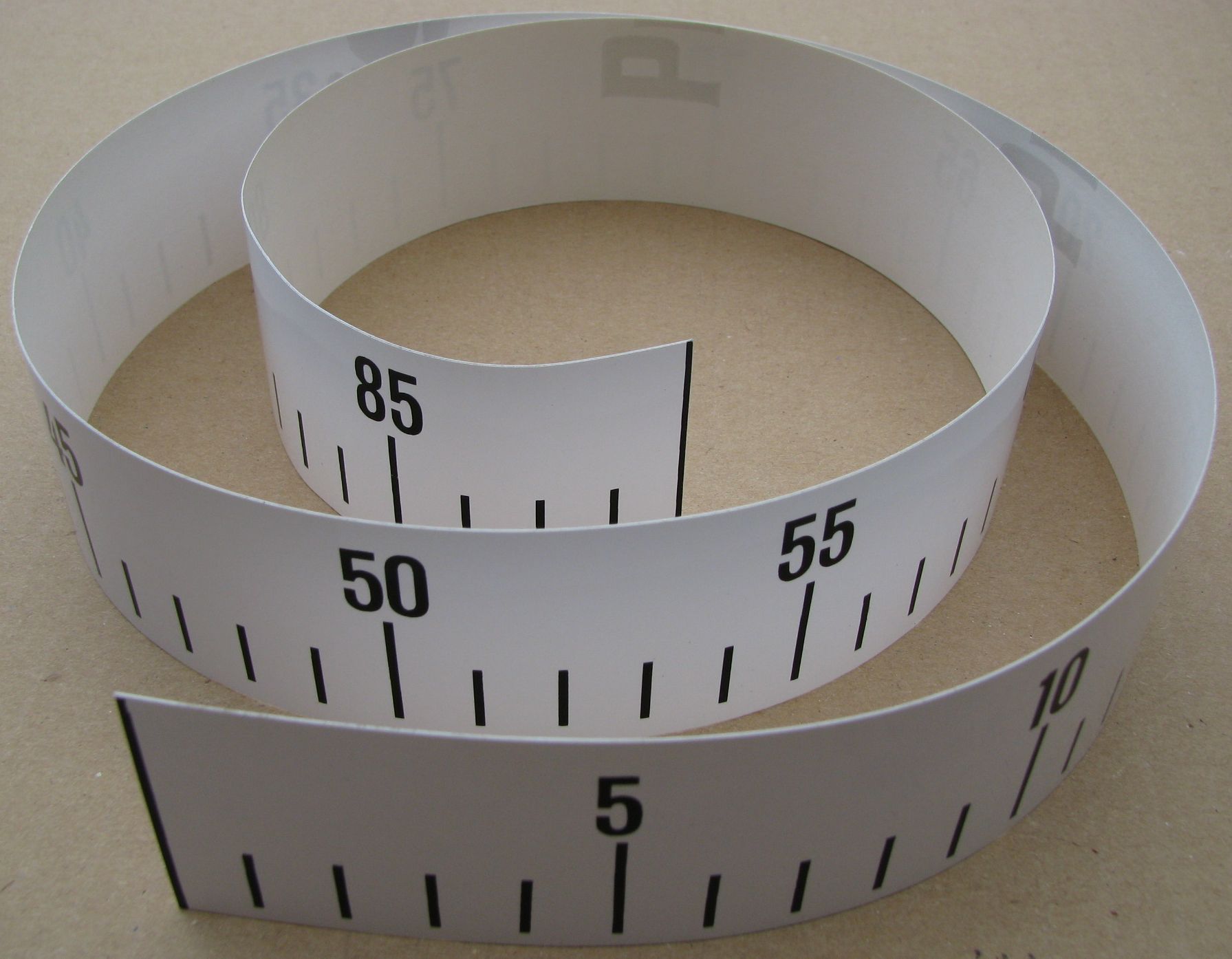 Aufgerolltes weißes selbstklebendes Maßband mit klarer Skala (Zahlen 5, 50, 55, 85 sichtbar), PVC-Band 88 cm, OSAGA Maßband für Koi-Wannen zur direkten Größenkontrolle in der Wanne