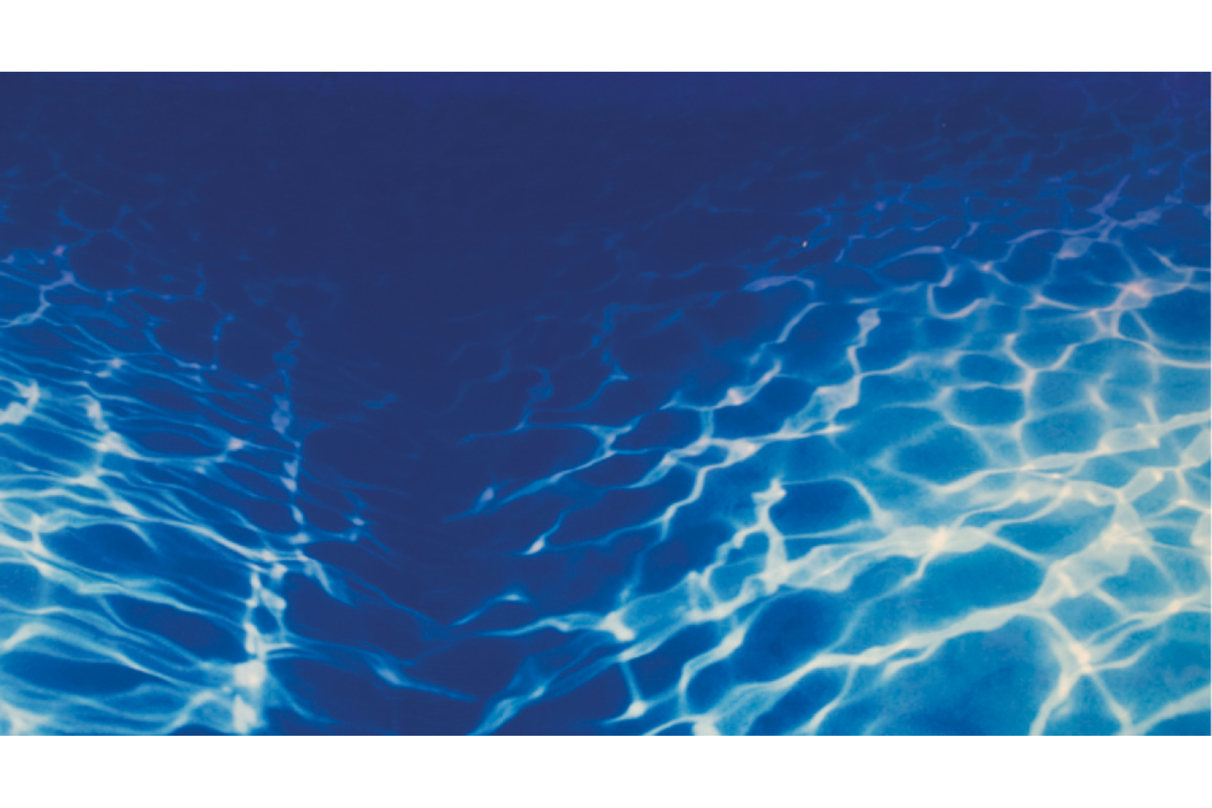 Nahaufnahme von Lichtreflexionen im blauen Wasser eines Schwimmbeckens