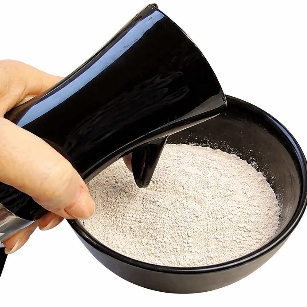Hand gießt Hobby Terrano Clay Powder weiß (Lehmpulver) in schwarze Schale; mineralisches Bindemittel für formstabile Terrarienböden, 1,3 kg