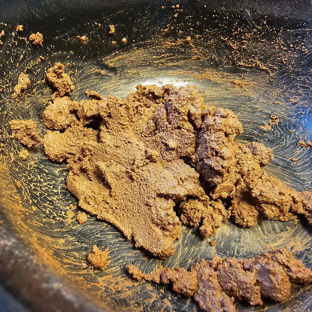 Nahaufnahme: feuchtes rotes Hobby Terrano Clay Powder Lehmpulver in Schale, vermischtes Substratbindemittel für Terrarienboden (1,3 kg), zeigt Konsistenz und Farbe